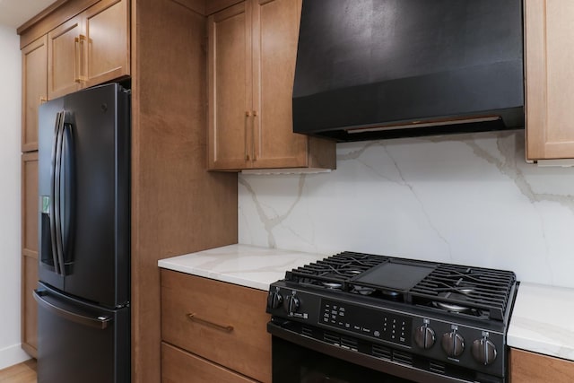 kitchen with extractor fan, decorative backsplash, brown cabinets, light stone counters, and black appliances