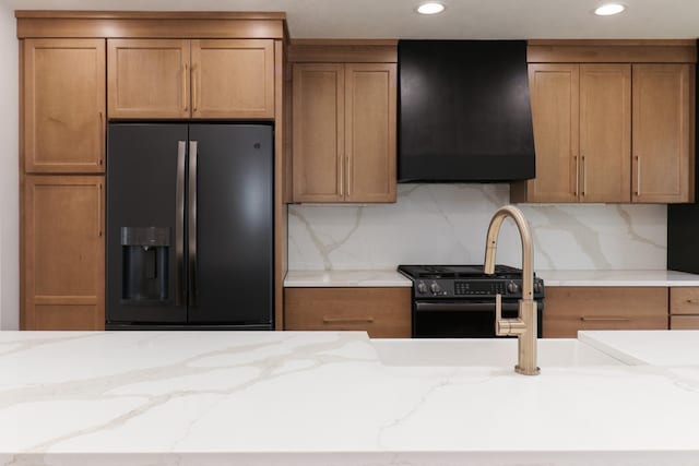 kitchen featuring brown cabinets, exhaust hood, and black appliances