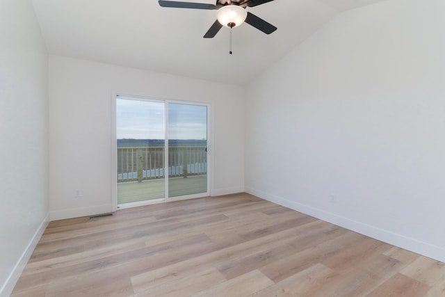 empty room featuring lofted ceiling, a ceiling fan, visible vents, and light wood-style floors