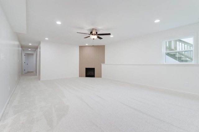 below grade area with recessed lighting, light carpet, baseboards, a large fireplace, and ceiling fan