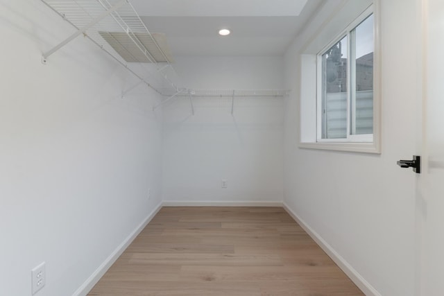 walk in closet with light wood-style floors