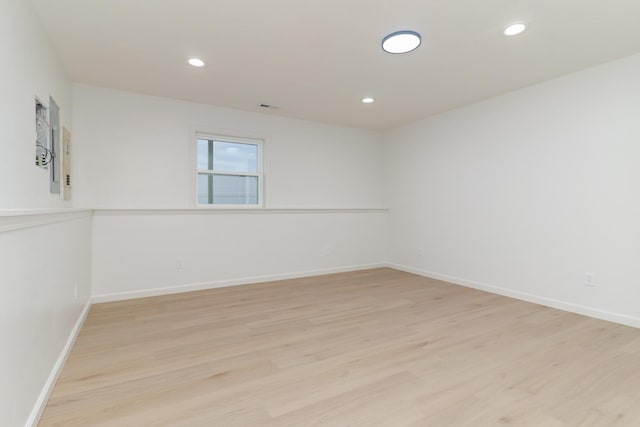 empty room featuring baseboards, light wood-style floors, visible vents, and recessed lighting