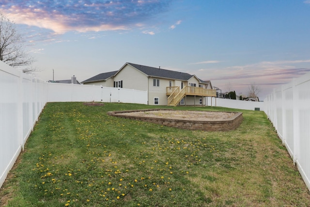 yard at dusk featuring a fenced backyard, a wooden deck, and stairs