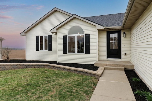 property entrance with a yard and roof with shingles