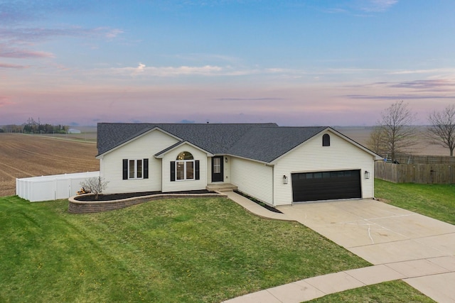 single story home featuring driveway, fence, an attached garage, a shingled roof, and a lawn