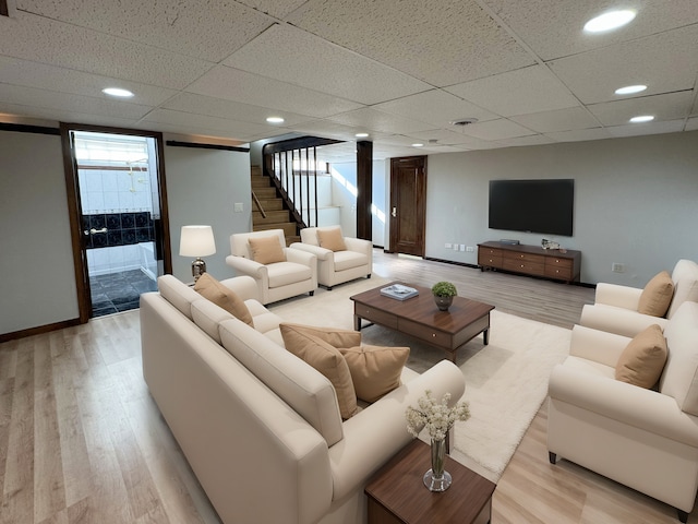 living room featuring a paneled ceiling and light wood-type flooring