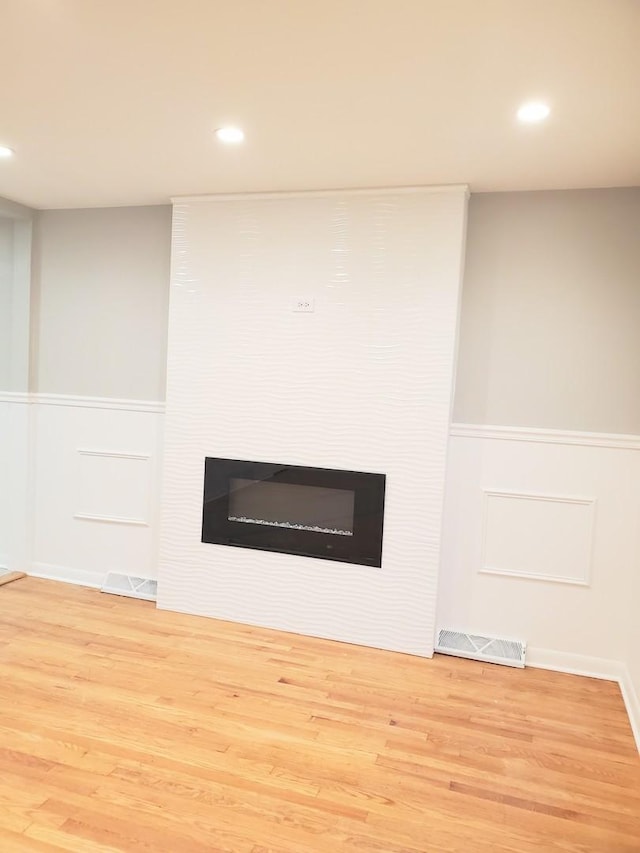 room details with a large fireplace and hardwood / wood-style floors