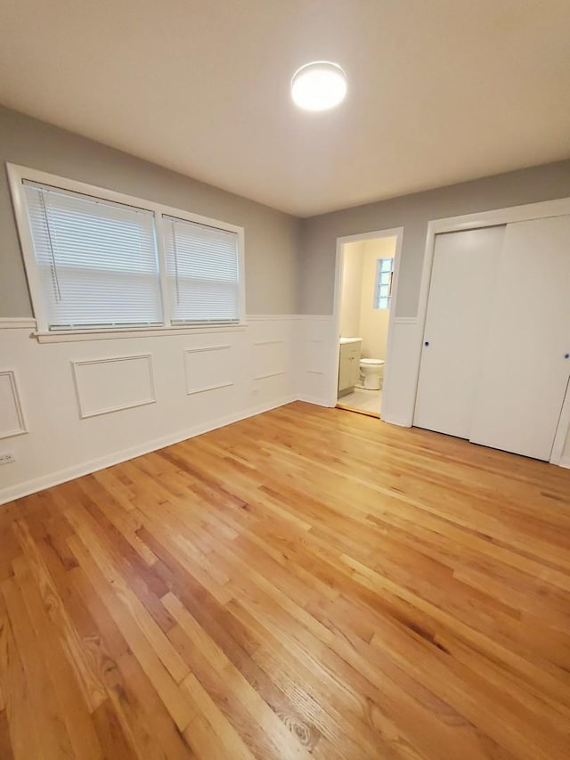 unfurnished bedroom with connected bathroom, a closet, and light wood-type flooring