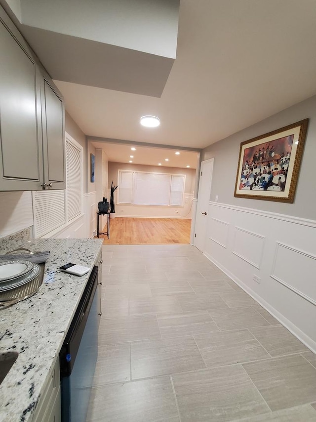 interior space with gray cabinetry, light stone countertops, and dishwasher