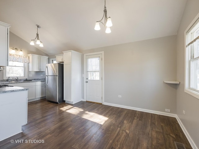 kitchen with white cabinetry, vaulted ceiling, stainless steel refrigerator, and decorative light fixtures