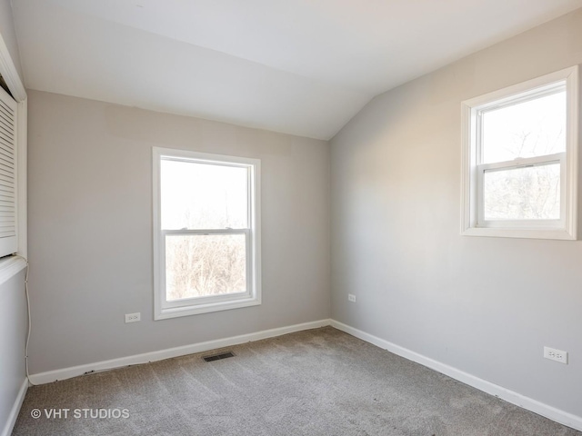 carpeted empty room featuring vaulted ceiling