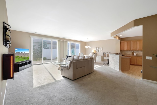 carpeted living room with an inviting chandelier