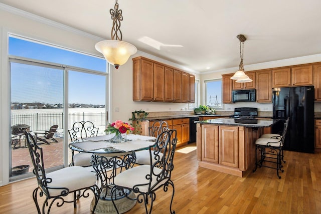 kitchen featuring crown molding, black appliances, decorative light fixtures, and a center island