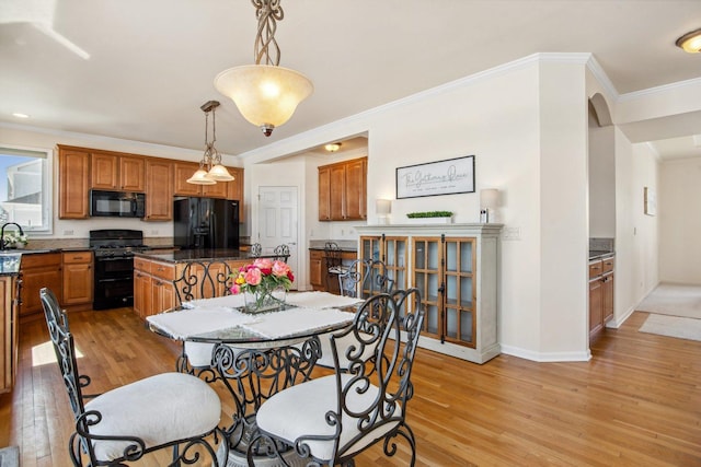 dining area with arched walkways, baseboards, crown molding, and light wood finished floors