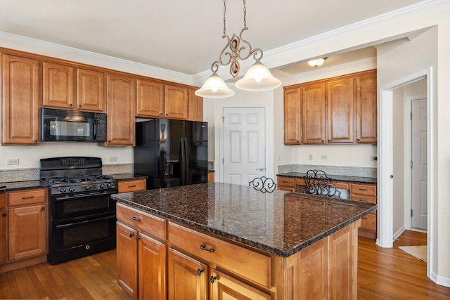 kitchen with brown cabinetry, light wood-style flooring, a center island, black appliances, and pendant lighting