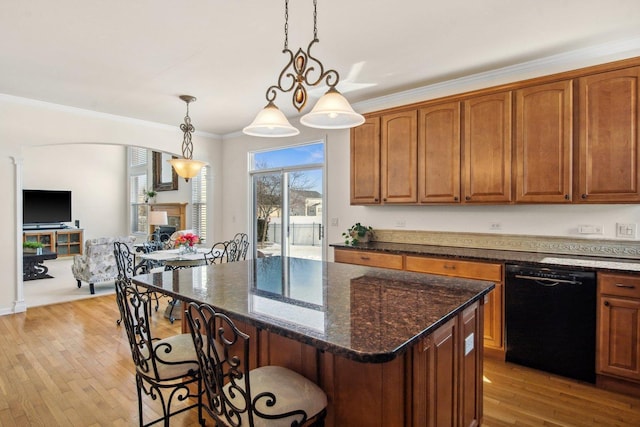 kitchen with a fireplace, a kitchen island, black dishwasher, hanging light fixtures, and brown cabinetry