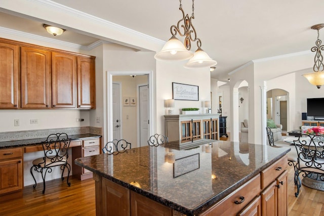 kitchen with dark wood-style floors, a center island, pendant lighting, and built in desk