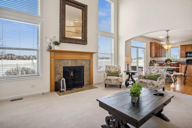 living area with arched walkways, baseboards, visible vents, and a high ceiling