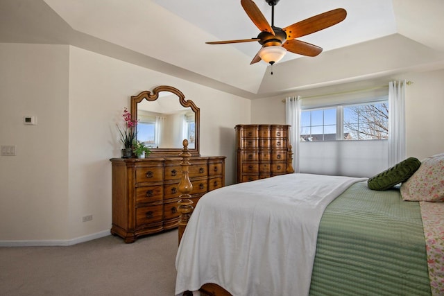 bedroom featuring ceiling fan, lofted ceiling, light colored carpet, baseboards, and a raised ceiling