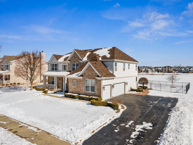 view of front of home with a residential view, aphalt driveway, an attached garage, fence, and brick siding