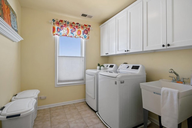 washroom featuring cabinet space, visible vents, a sink, separate washer and dryer, and baseboards