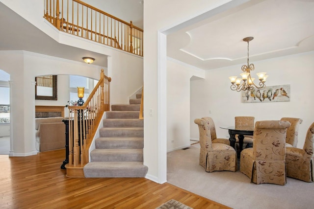 dining area with arched walkways, stairway, ornamental molding, wood finished floors, and baseboards