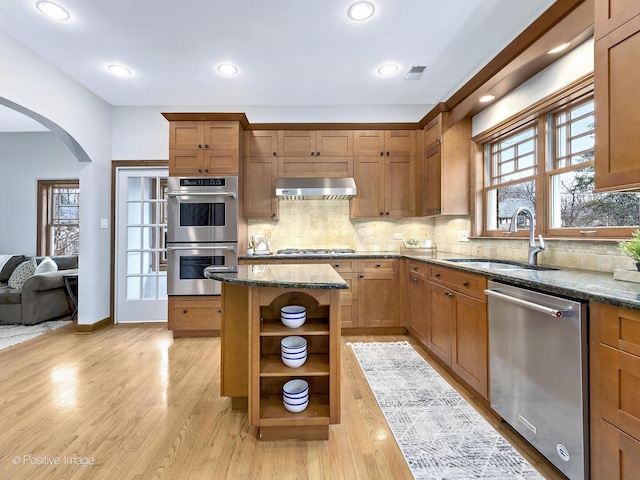 kitchen featuring extractor fan, a sink, appliances with stainless steel finishes, dark stone counters, and open shelves