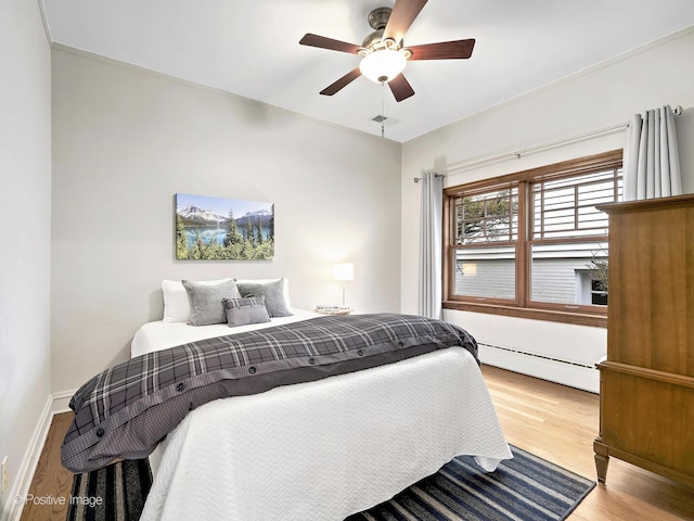 bedroom featuring visible vents, baseboards, ceiling fan, wood finished floors, and baseboard heating