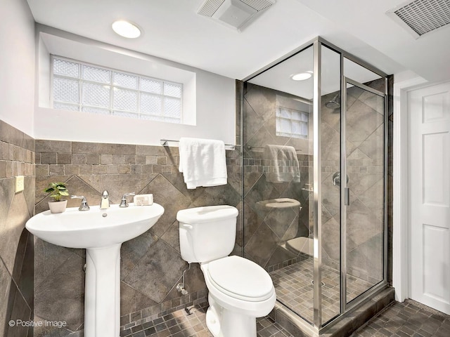 full bathroom featuring plenty of natural light, visible vents, toilet, a shower stall, and tile walls