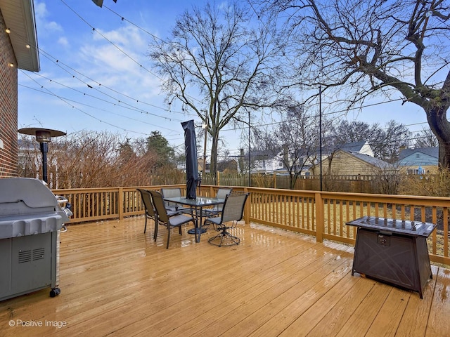 wooden deck featuring a grill, fence, and outdoor dining area