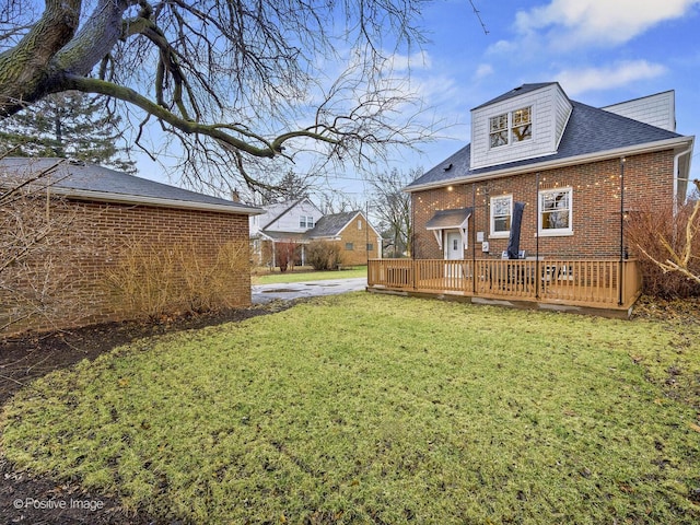 back of house with brick siding, a yard, and a wooden deck