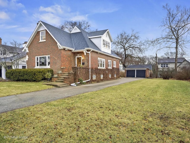 view of front of house featuring brick siding, an outdoor structure, a detached garage, and a front lawn