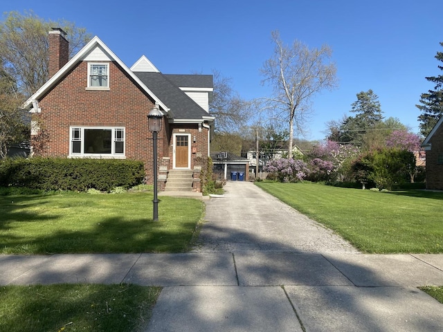 view of front facade featuring brick siding, a front lawn, a chimney, and a shingled roof