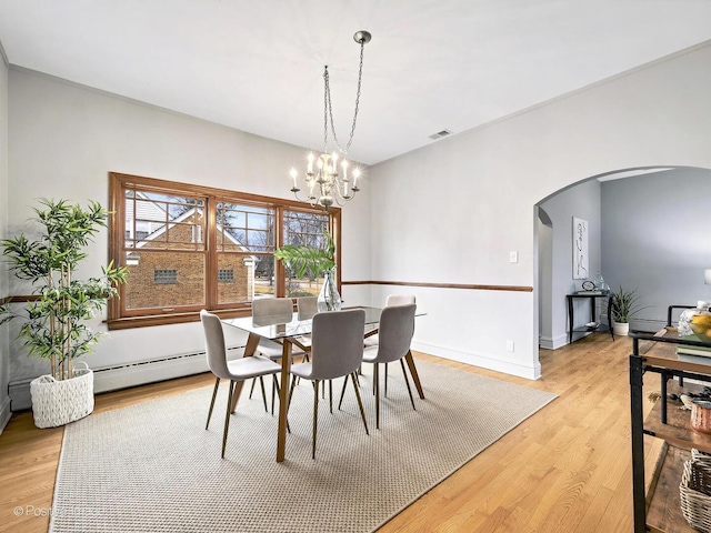 dining area featuring light wood finished floors, visible vents, arched walkways, baseboards, and an inviting chandelier