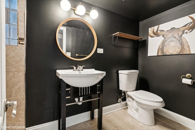 bathroom featuring toilet, tile patterned flooring, baseboards, and a sink