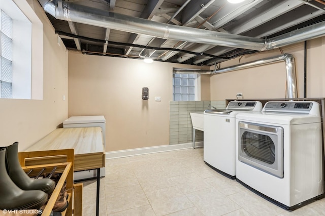 clothes washing area with light tile patterned floors, laundry area, washing machine and clothes dryer, and baseboards