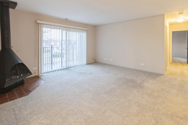 unfurnished living room with carpet and a wood stove