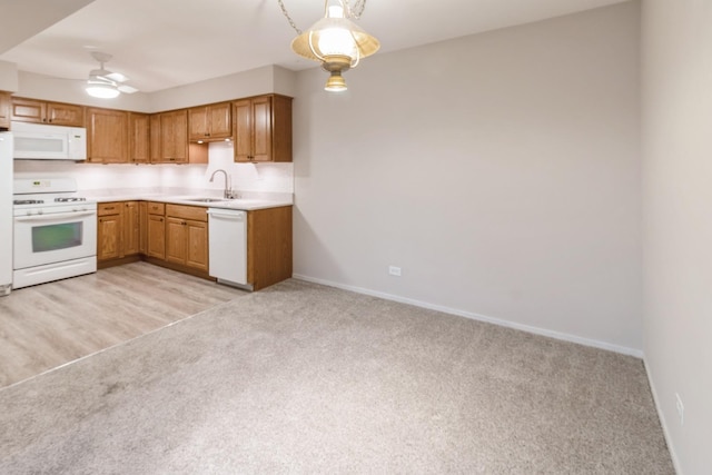 kitchen with sink, hanging light fixtures, light colored carpet, ceiling fan, and white appliances