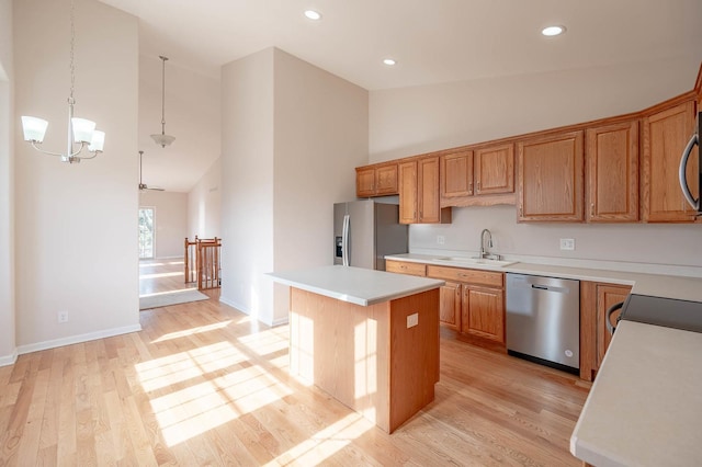 kitchen with sink, hanging light fixtures, stainless steel appliances, a center island, and light hardwood / wood-style floors