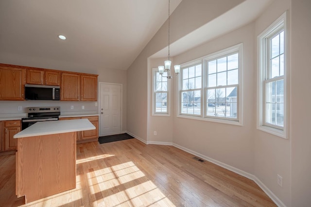 kitchen with light hardwood / wood-style flooring, appliances with stainless steel finishes, an inviting chandelier, hanging light fixtures, and a center island