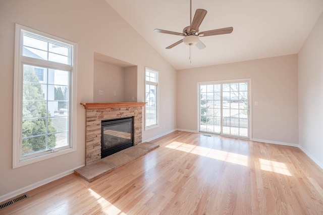 unfurnished living room featuring high vaulted ceiling, a stone fireplace, light hardwood / wood-style floors, and ceiling fan