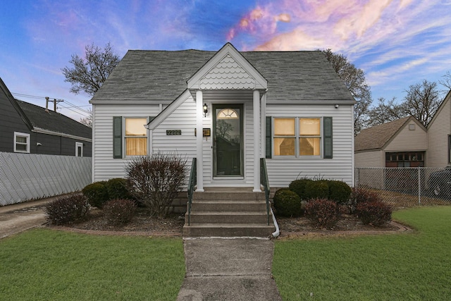 view of front of house with entry steps, fence, and a lawn