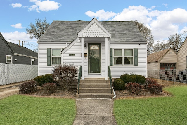 bungalow featuring fence, a front lawn, and roof with shingles