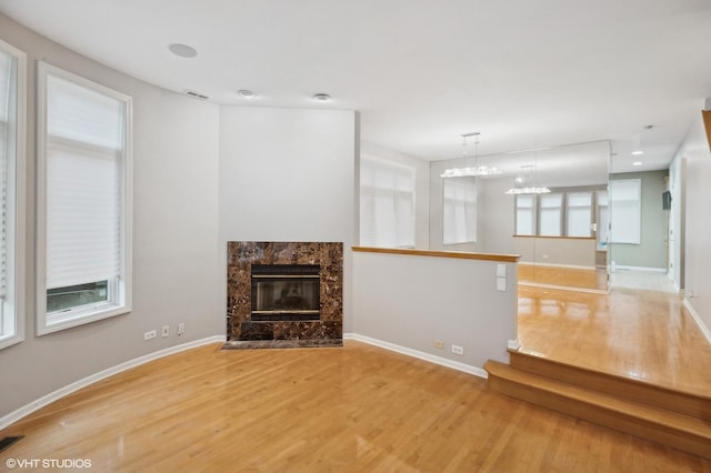 unfurnished living room with light wood-type flooring and a high end fireplace