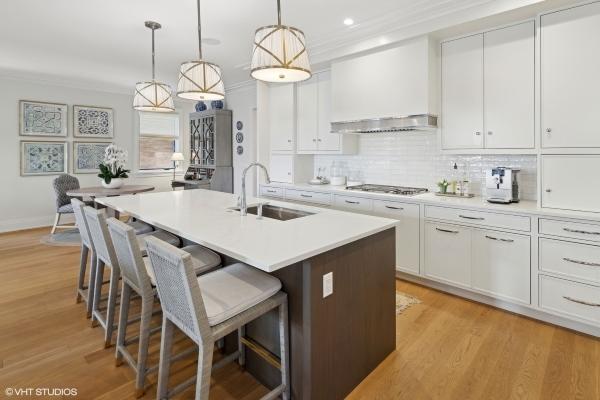 kitchen featuring white cabinets, ornamental molding, a kitchen breakfast bar, stainless steel gas stovetop, and a sink