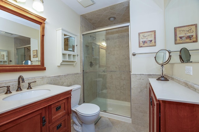 bathroom featuring walk in shower, vanity, toilet, and tile walls