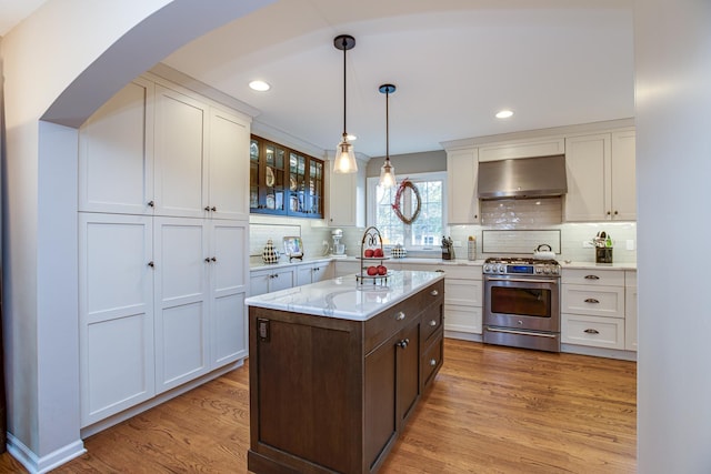 kitchen featuring dark brown cabinetry, hanging light fixtures, high end stainless steel range oven, light hardwood / wood-style floors, and exhaust hood