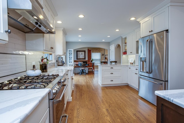 kitchen with white cabinetry, appliances with stainless steel finishes, sink, and range hood