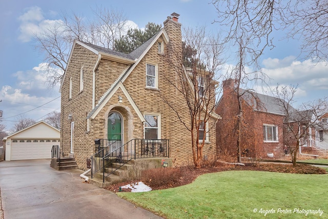 tudor home featuring a garage, an outdoor structure, and a front lawn