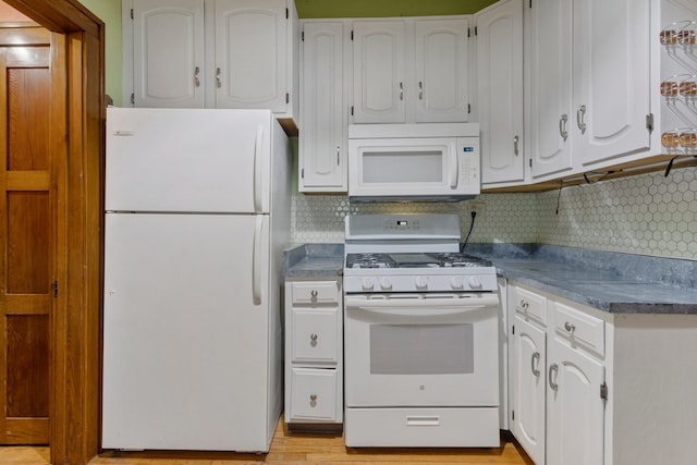 kitchen featuring tasteful backsplash, dark countertops, white appliances, and white cabinets